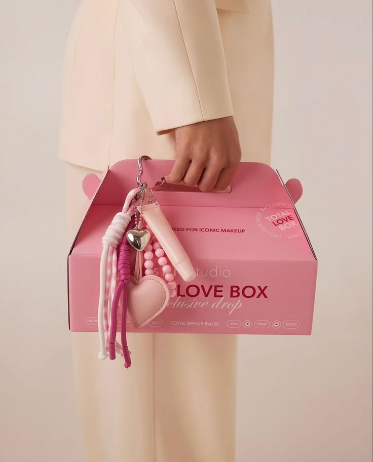 Caja de marca con asa y accesorios colgantes, sostenida en la mano